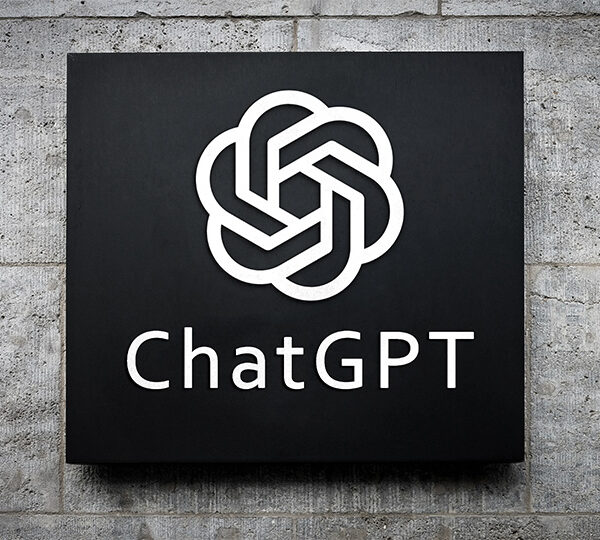 Bildbeschreibung: Ein schwarzes Schild mit dem ChatGPT-Logo und Schriftzug, montiert an einer Betonwand.